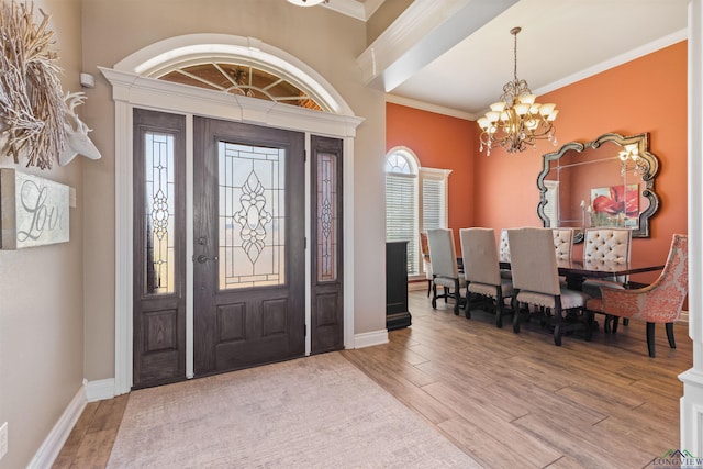 foyer entrance with a healthy amount of sunlight, ornamental molding, wood finished floors, and a chandelier