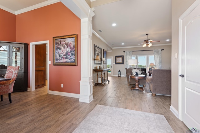 interior space with ornate columns, ornamental molding, a ceiling fan, and wood finished floors