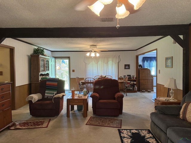 living room featuring beamed ceiling, ceiling fan, and a textured ceiling