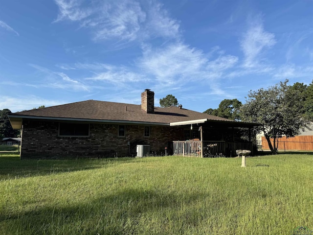 rear view of property featuring a lawn and central air condition unit