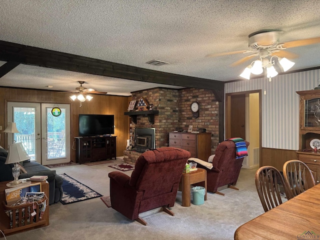 carpeted living room featuring beamed ceiling, french doors, a textured ceiling, and a wood stove