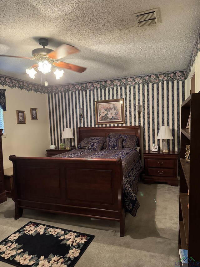 bedroom with ceiling fan, carpet floors, and a textured ceiling