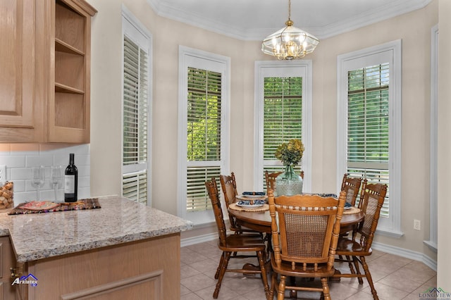 dining area featuring light tile patterned flooring, ornamental molding, and an inviting chandelier