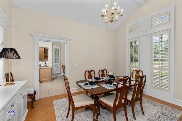 dining area with an inviting chandelier, lofted ceiling with beams, and light wood-type flooring