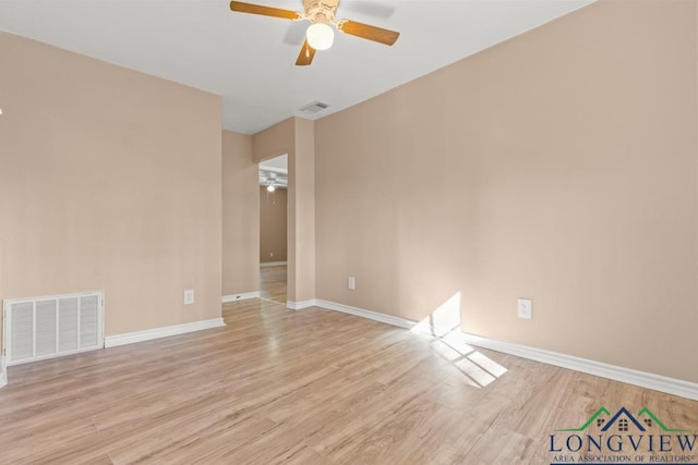 spare room featuring a ceiling fan, visible vents, light wood finished floors, and baseboards