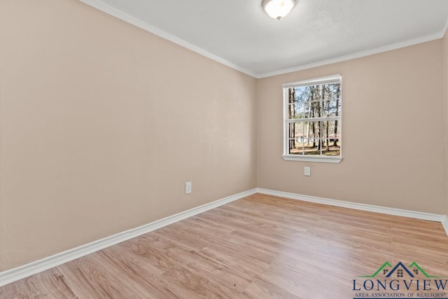 spare room featuring crown molding, baseboards, and wood finished floors