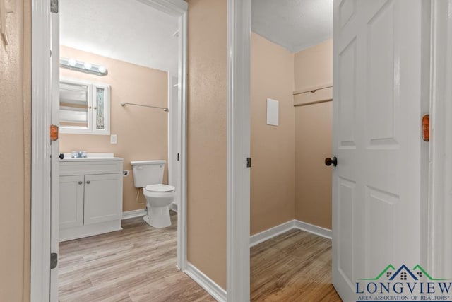 bathroom with baseboards, toilet, wood finished floors, and vanity