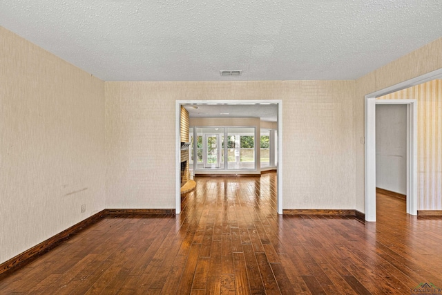 spare room featuring a fireplace, dark hardwood / wood-style flooring, and a textured ceiling