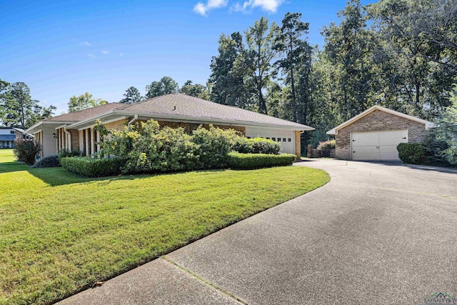 single story home featuring a garage, an outbuilding, and a front lawn