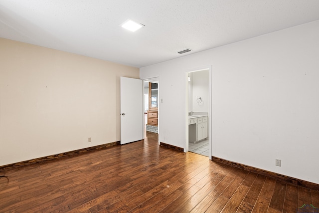 unfurnished bedroom featuring dark wood-type flooring and ensuite bath