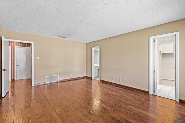 empty room with wood-type flooring and a textured ceiling