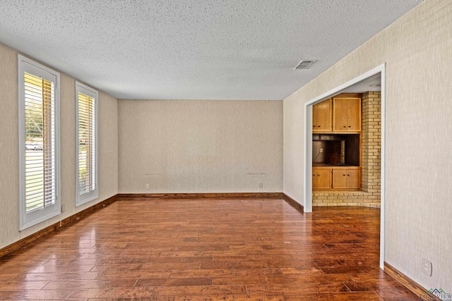 unfurnished living room with a textured ceiling, dark hardwood / wood-style floors, and a healthy amount of sunlight