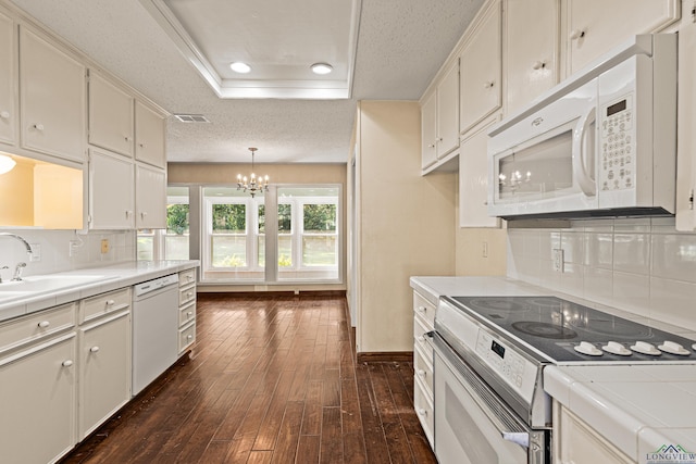 kitchen with tile countertops, white appliances, backsplash, hanging light fixtures, and a tray ceiling