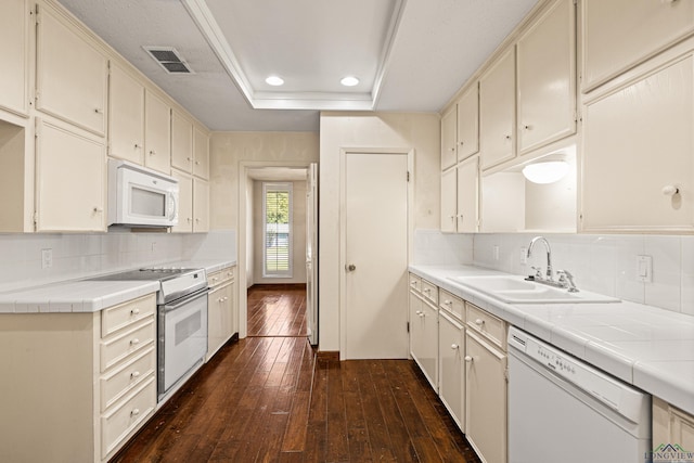 kitchen featuring a raised ceiling, tile countertops, sink, and white appliances