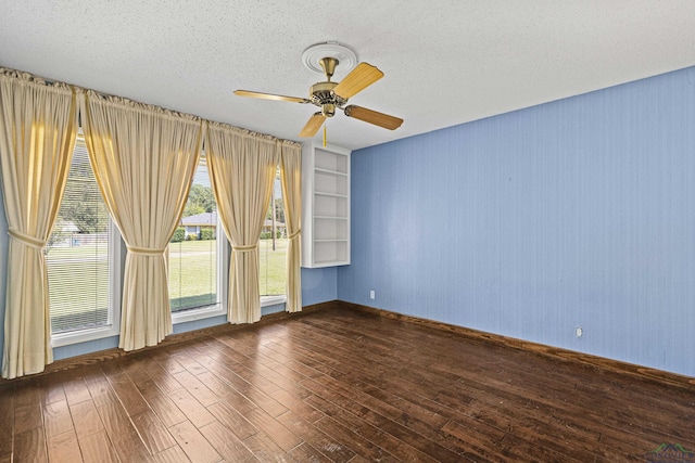 unfurnished room featuring a textured ceiling, built in shelves, ceiling fan, and dark hardwood / wood-style floors