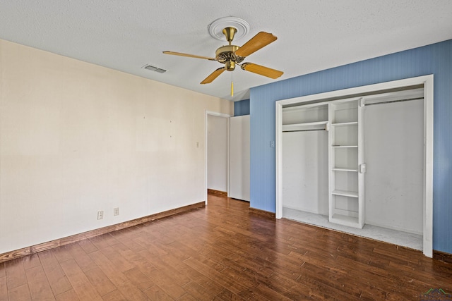 unfurnished bedroom featuring a textured ceiling, ceiling fan, a closet, and dark hardwood / wood-style floors