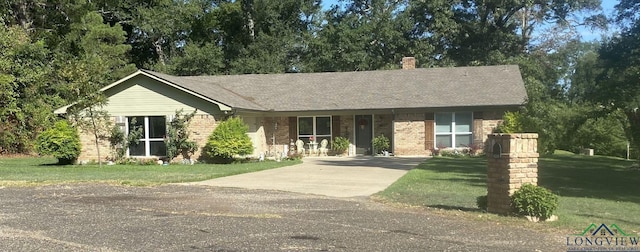 single story home featuring concrete driveway, brick siding, a chimney, and a front lawn