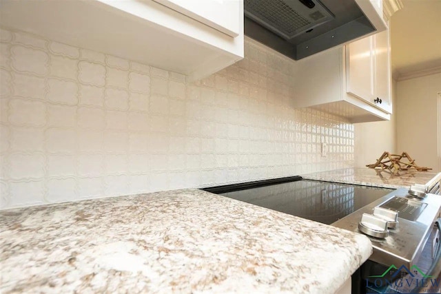 kitchen with crown molding, exhaust hood, light stone countertops, and white cabinets