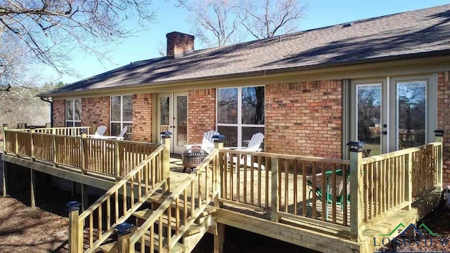 back of property with brick siding, a shingled roof, a chimney, and a deck
