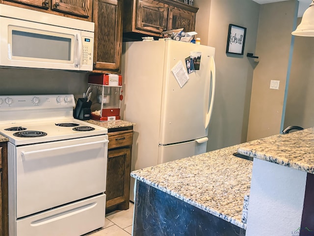 203 Reynolds St, Pittsburg, TX 75686 - kitchen featuring white appliances, dark brown cabinets, light stone counters, and light tile patterned floors