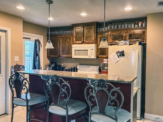 203 Reynolds St, Pittsburg, TX 75686 - kitchen featuring white appliances, dark brown cabinetry, a kitchen bar, light stone counters, and light tile patterned floors