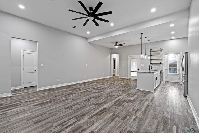 unfurnished living room featuring ceiling fan, sink, and dark wood-type flooring