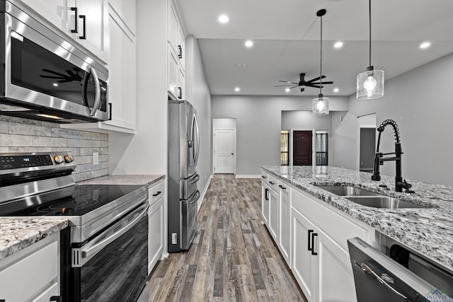 kitchen with white cabinetry, sink, ceiling fan, light stone counters, and appliances with stainless steel finishes