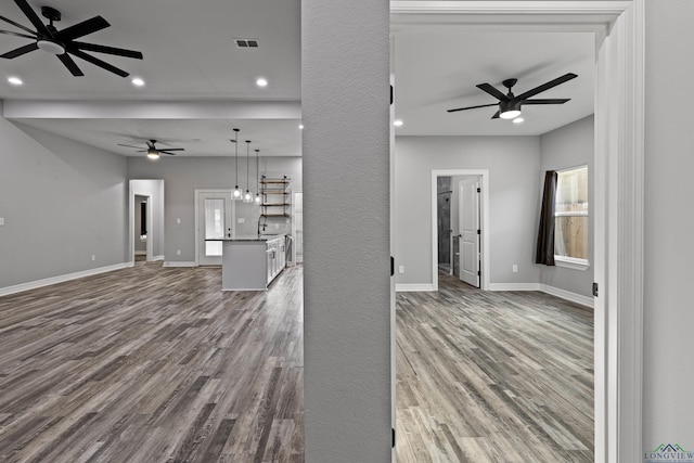 unfurnished living room featuring ceiling fan, sink, and hardwood / wood-style flooring