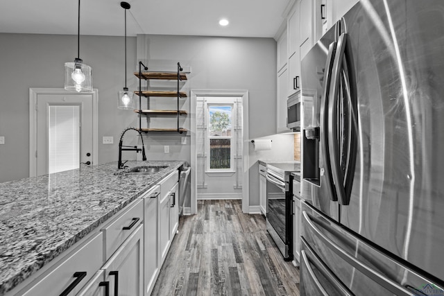 kitchen featuring white cabinetry, sink, light stone counters, decorative light fixtures, and appliances with stainless steel finishes