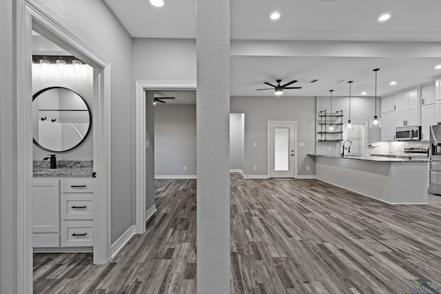 unfurnished living room featuring ceiling fan, dark hardwood / wood-style flooring, and sink