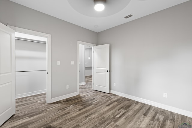 unfurnished bedroom with ceiling fan, dark hardwood / wood-style flooring, and a closet