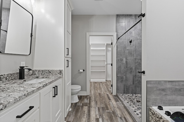 bathroom with a tile shower, vanity, hardwood / wood-style flooring, and toilet