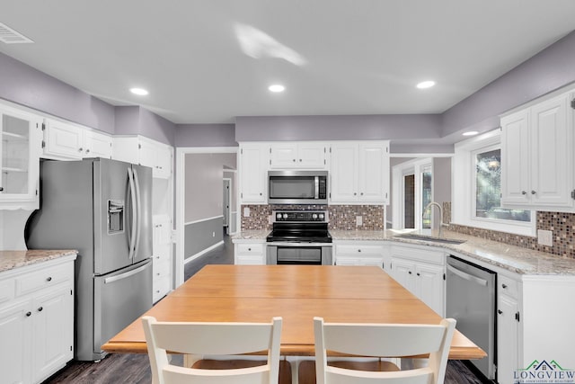 kitchen with white cabinets, sink, decorative backsplash, light stone countertops, and stainless steel appliances