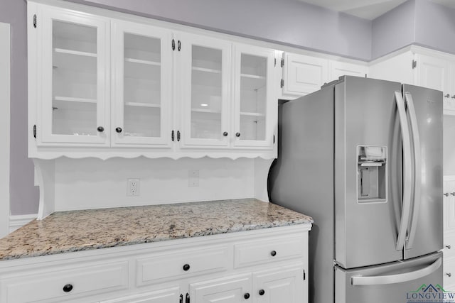 kitchen with white cabinets, stainless steel fridge, and light stone countertops