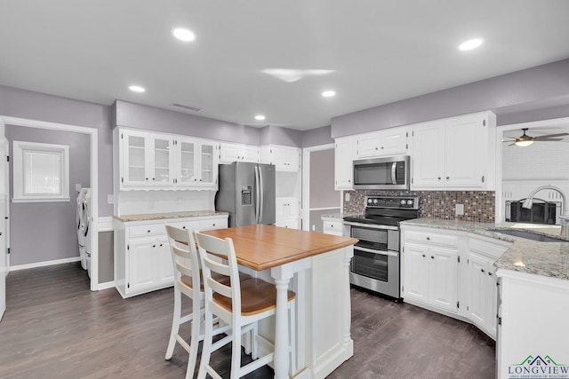 kitchen featuring washing machine and dryer, stainless steel appliances, white cabinetry, and sink