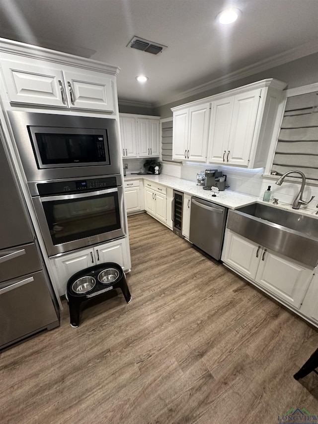 kitchen featuring crown molding, appliances with stainless steel finishes, sink, and white cabinets