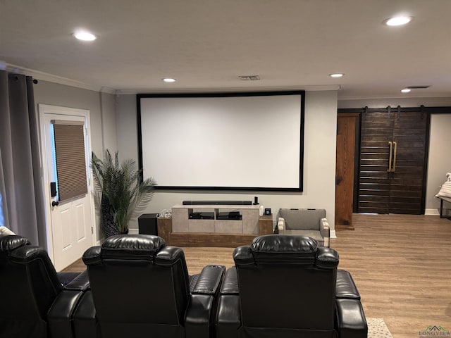 home theater featuring ornamental molding, a barn door, and hardwood / wood-style floors