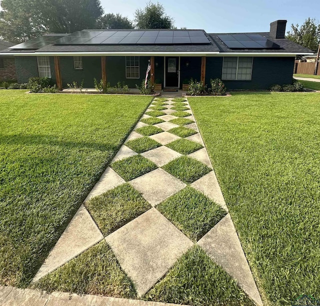 view of front of house with a front yard, solar panels, and a porch