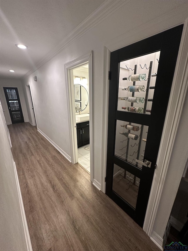 corridor with wood-type flooring, sink, and crown molding