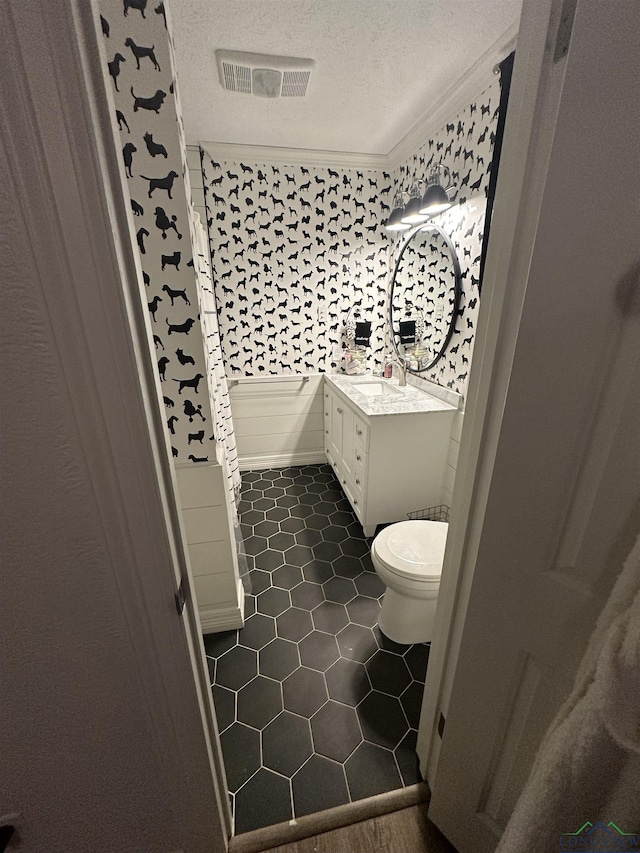 bathroom featuring vanity, ornamental molding, toilet, and a textured ceiling