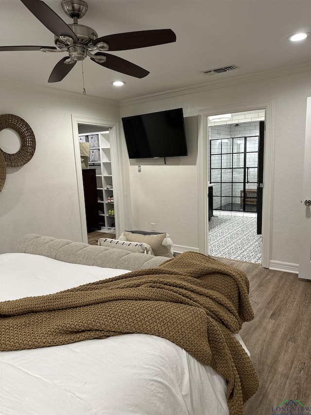 bedroom with wood-type flooring, ornamental molding, a spacious closet, ceiling fan, and a closet