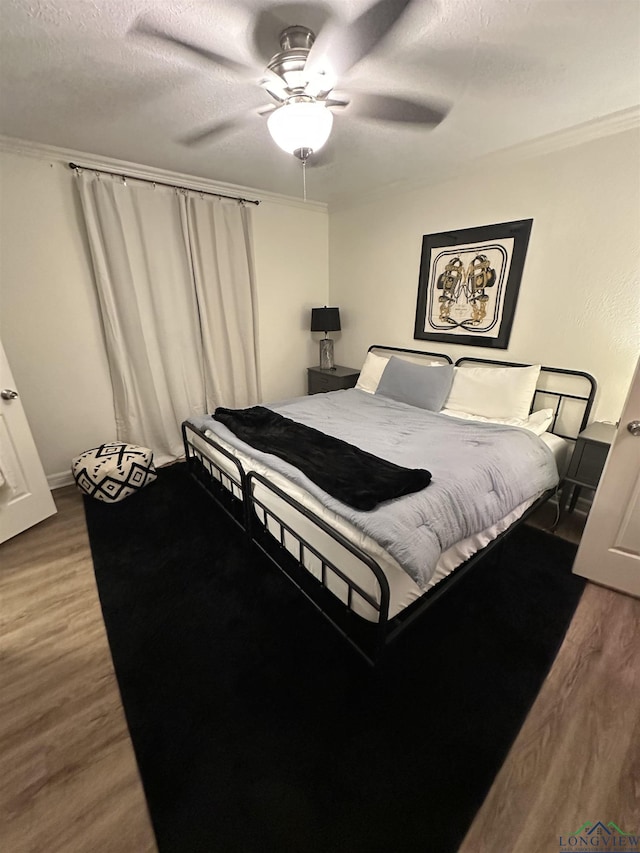 bedroom featuring crown molding, a textured ceiling, ceiling fan, and hardwood / wood-style flooring