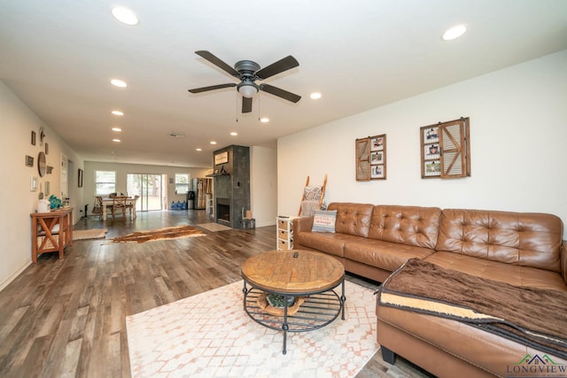 living area featuring wood finished floors, baseboards, recessed lighting, ceiling fan, and a large fireplace