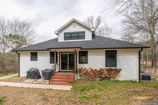 view of front of house with a front lawn, central AC, and roof with shingles