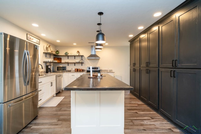 kitchen featuring dark wood finished floors, stainless steel appliances, wall chimney range hood, and open shelves