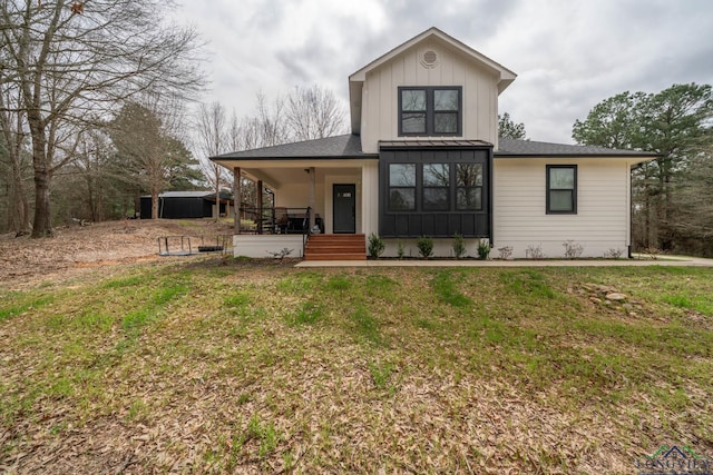 rear view of property with a yard, board and batten siding, an outdoor structure, and a porch