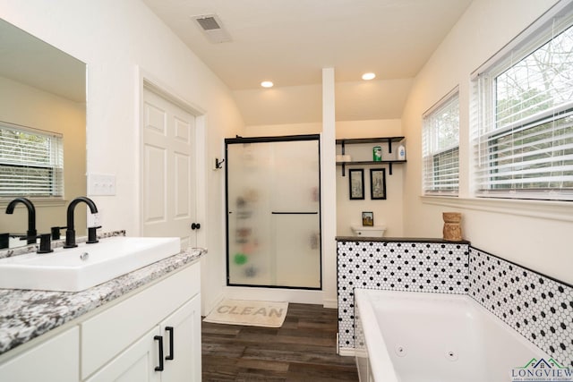 full bath with vanity, wood finished floors, visible vents, a tub with jets, and a stall shower