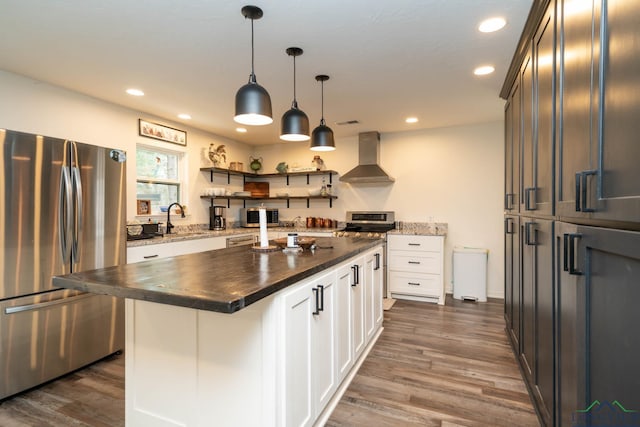 kitchen with dark wood finished floors, recessed lighting, stainless steel appliances, and wall chimney exhaust hood