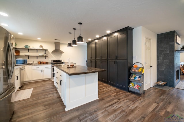 kitchen featuring a kitchen island, wall chimney range hood, dark wood-style flooring, appliances with stainless steel finishes, and open shelves