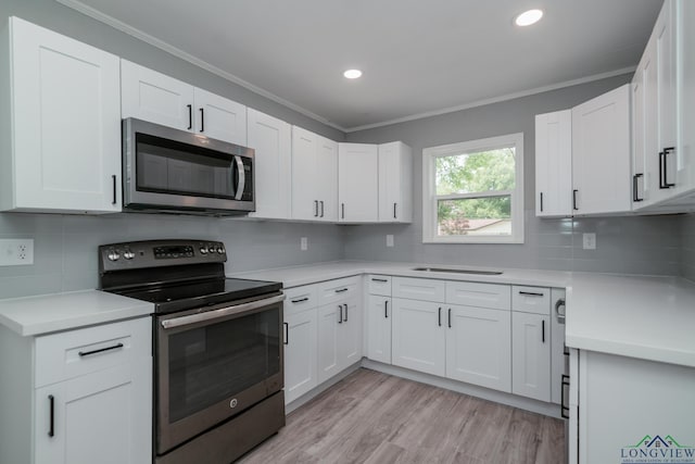 kitchen featuring decorative backsplash, white cabinets, stainless steel appliances, and ornamental molding